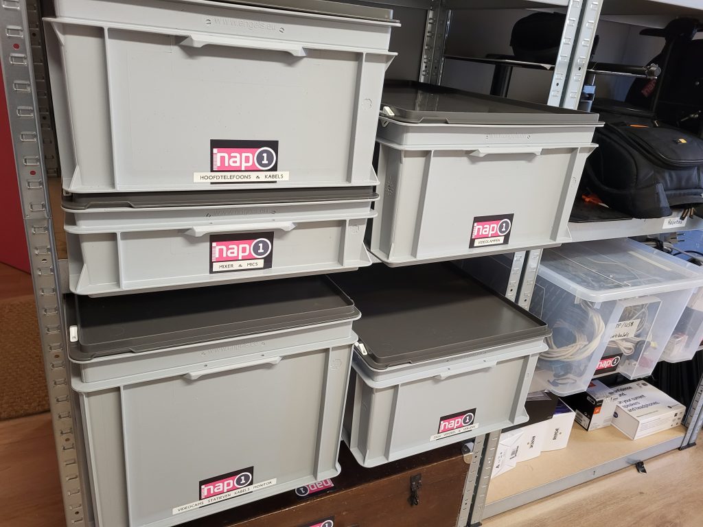 Grijze plastic kisten met stickers van NAP1 erop.