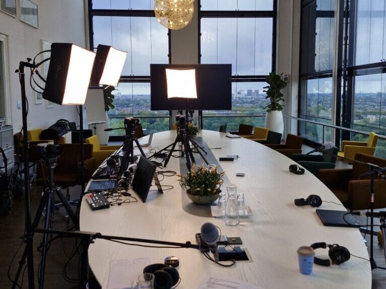 Tafel met microfoons, camera's en videolampen erom heen.